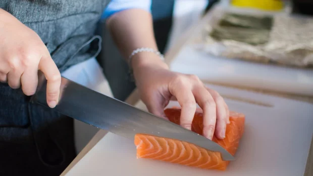 Person Slicing Meat On White Chopping Board