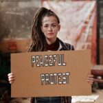 A Woman Holding a Cardboard with Words Written on Her Face