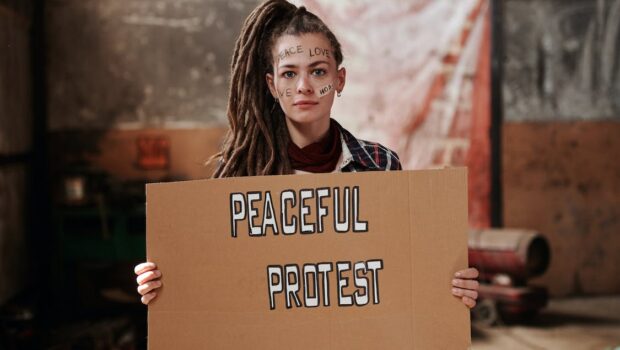 A Woman Holding a Cardboard with Words Written on Her Face