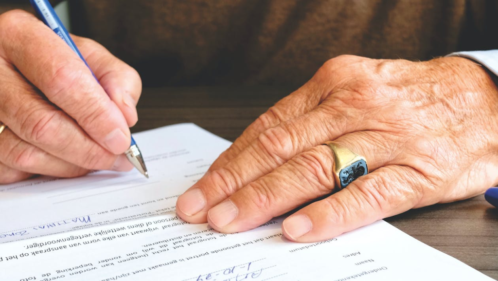 old man writing something on paper.