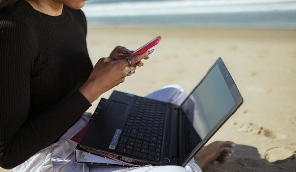 A person sitting on the beach using a computer