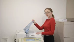 Serious female office worker using printer in workplace