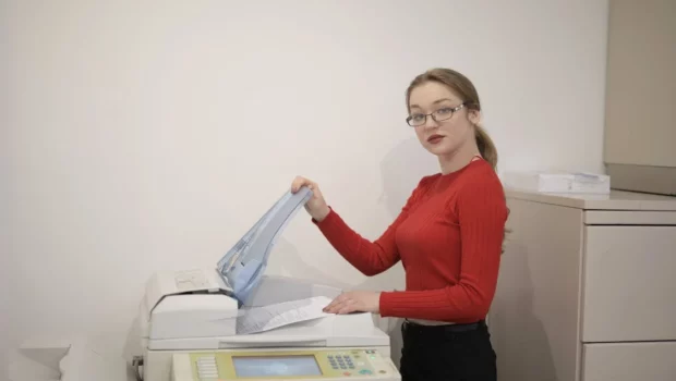 Serious female office worker using printer in workplace