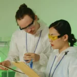 A Man and a Woman Wearing Personal Protective Equipment Holding Clipboards and checking protein expression